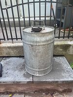 Front view showing the completed cylindrical galvanized metal fuel can with CPR embossing and wooden-handled metal carry handle.