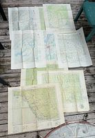 Overview of eight folded vintage USGS topographic maps laid out on wooden surface, showing different regions in Ontario with various towns, lakes, and geographical features.