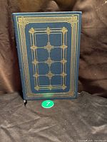 Front cover of the leather-bound book with gold ornamental design on dark blue leather.