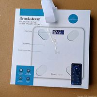 Front of sealed box showing Brookstone Smart Scale Health Monitor