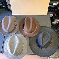 Top view of four wool felt fedoras showing colours and bands