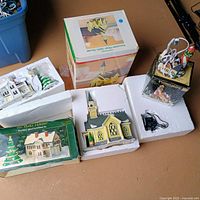Group view of all ceramic village buildings, trees, packaging and boxes
