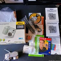 Full contents showing camera, box, manuals, CDs, cables, memory card