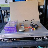 Front view of Panasonic DMR-ES35V with accessories and VHS tapes displayed