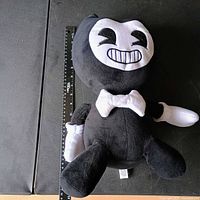 Full view of Bendy plush beside ruler for scale