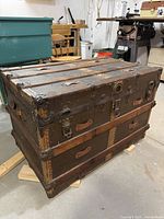 front and side view of antique wood steamer trunk showing brass hardware and slat construction