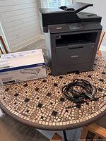 Printer, toner cartridge box, power cable on table