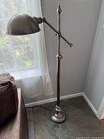 Full view of brushed nickel floor lamp beside sofa