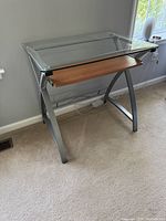 Front view of glass top desk showing keyboard shelf and metal frame