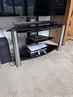 Front view of black glass TV stand holding electronics