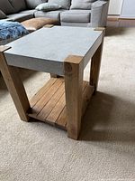 Three-quarter view showing wood legs, silver laminate top, lower shelf