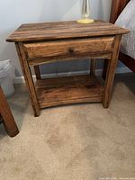 Front view of wood side table showing drawer closed and lower shelf