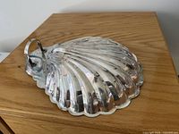Shell-shaped dish upside down showing scalloped rim and loop handle