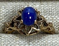 Front view showing blue star sapphire cabochon in star-motif setting with filigree shoulders