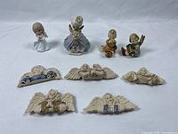 Lot of 9 angel-themed items including 4 small angel figurines, 1 Precious Moments angel figurine, and 5 angel fridge magnets with cherubs and wings