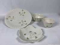 The full group of Belleek pieces including serving plate, leaf plate, small bowl, and dip cup all with shamrock decoration.