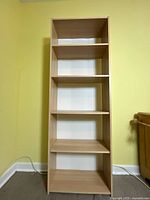 Front view of the wooden book shelf showing five shelves and natural wood finish with white back panel.
