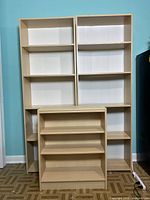 Front view of two tall wooden bookshelves side by side with the shorter bookshelf in front.
