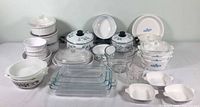 Complete lot showing all CorningWare and Pyrex dishes arranged on table including bowls, casseroles, measuring cup, and lids.