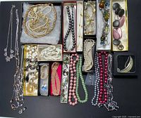 Photo showing full lot of costume necklaces, earrings, bracelet, and pendant arranged on a black background