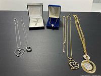Overview of assorted necklaces including items in display boxes and various pendants and chain lengths arranged on a flat surface