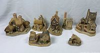 Front to back view of all seven David Winter cottages displayed in single row, showing details and scale.