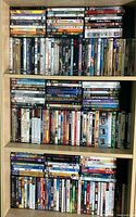 Shelf of assorted DVDs showing various titles: classics, comedies, dramas, and collections, stacked side by side and on top of each other.