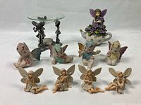 Metal wax melter with fairy figures, Denzine 'The Fairy Tea Pot' fairy figure, vintage 'Sugar Baby' fairy butterflies, and resin fairy figures arranged on a white backdrop.