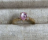 Top view of ring showing pear-shaped pink center stone flanked by two round diamonds in 10K yellow gold