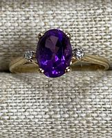 Front-facing close-up of ring showing oval purple amethyst and two round accent stones