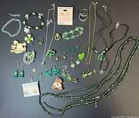 Top-down image showing entire assortment of Irish themed jewelry including bracelets, necklaces, earrings, pins, and rings arranged on black background