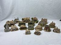 Front view of 15 assorted miniature cottages and buildings arranged in three rows on white background