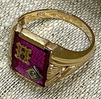 Front angle view showing red glass inlay with letter H and square diamond chip setting