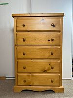 Front view of pine highboy dresser showing five drawers and wooden knobs.