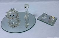 All Swarovski crystal figurines displayed on round and square mirrors, including the hedgehog, tall dog, two small bears, and birthday cake.