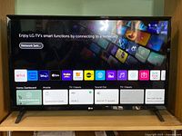 LG 32-inch smart TV powered on showing the home screen with various apps and input options.