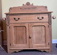 Front view of the entire stripped Victorian wood washstand showing drawer, two door cabinet, and ornate top piece.