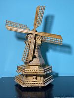 Front side view of wooden windmill music box showing lattice blades and base detail.