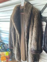 Full view of brown fur coat hanging, showing length and lining