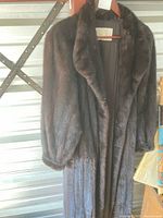 Front view of brown full-length fur coat on hanger showing overall style and length
