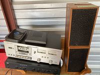 Front view showing Marantz cassette deck, AMC amplifier, small black component on top, and two stacked wood speakers