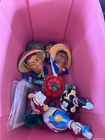 Overview of pink bin showing wall plaque heads, figurine decanters, apple container and other pieces