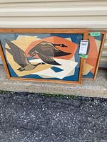 Both framed abstract geese prints leaning against wall