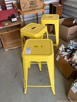 Three yellow metal stools front view