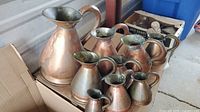 Group shot of nine copper pitchers and jugs