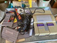 Console, controller, cabling and several game cartridges on tray