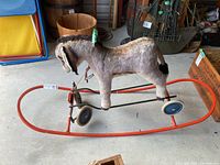 Full view of plush donkey ride-on on red metal sled frame