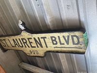 Full sign leaning against corrugated wall showing text and shape