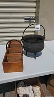 Wooden box with compartments beside cast iron cauldron