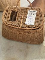 Full view of wicker fishing basket showing shape, handle, lid and tag